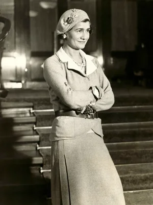 Gabrielle-Coco-Chanel-in-suit-and-beret.webp