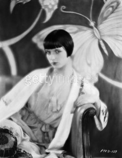 1928 sitting on an armchair in front of a screen decorated with butterflies.jpg