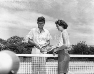 1955 06 27 stand on either side of a tennis net, holding tennis racquets, Hyannis Port.jpg